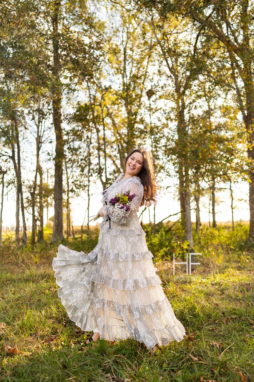A dreamy outdoor portrait showcasing a ruffled white lace gown against golden autumn trees.