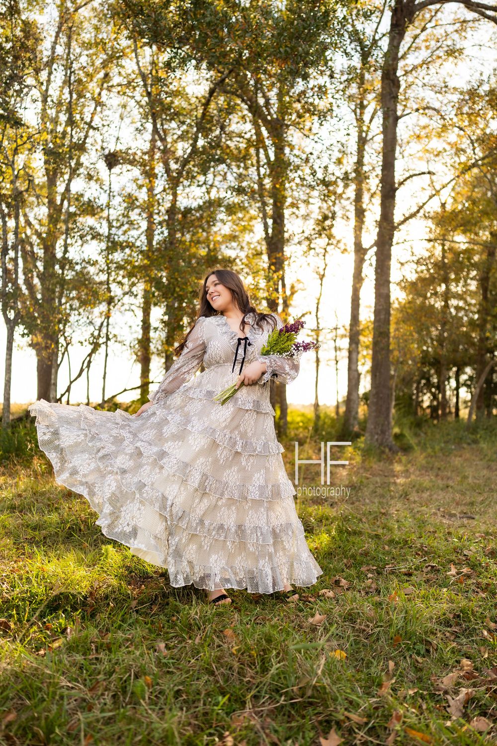 A romantic forest scene with a flowing white lace dress twirling in golden afternoon light.