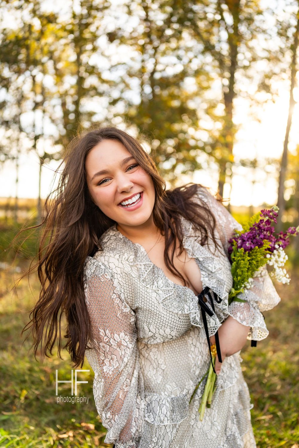 A candid outdoor portrait with natural light featuring a detailed lace dress and wildflower bouquet.