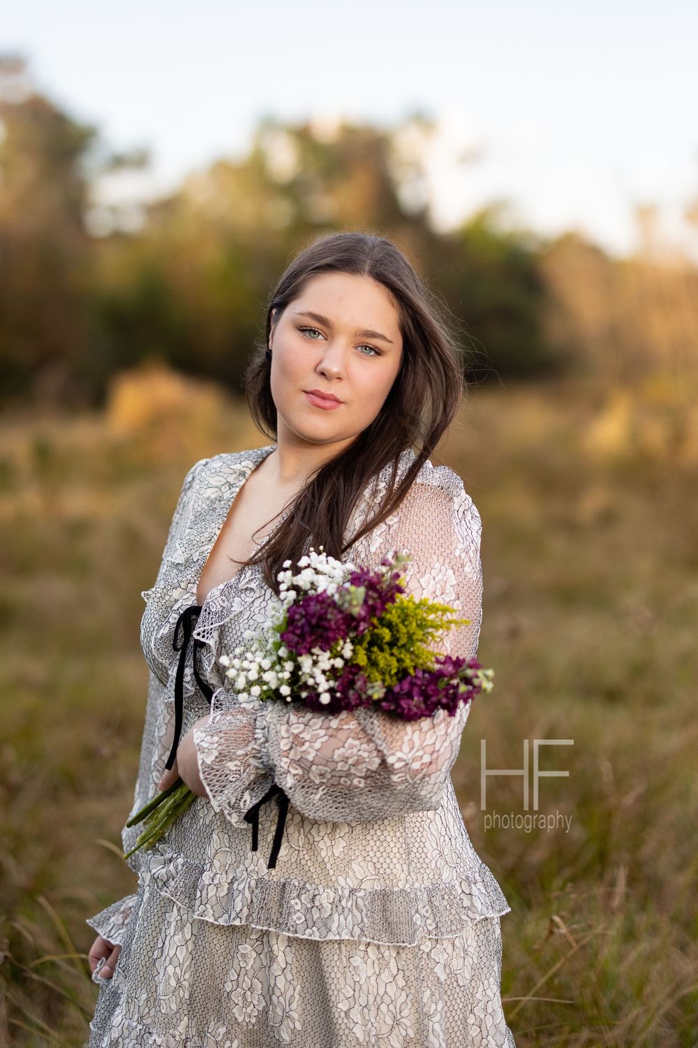 An elegant autumn portrait featuring delicate lace details and a vibrant purple and white bouquet.