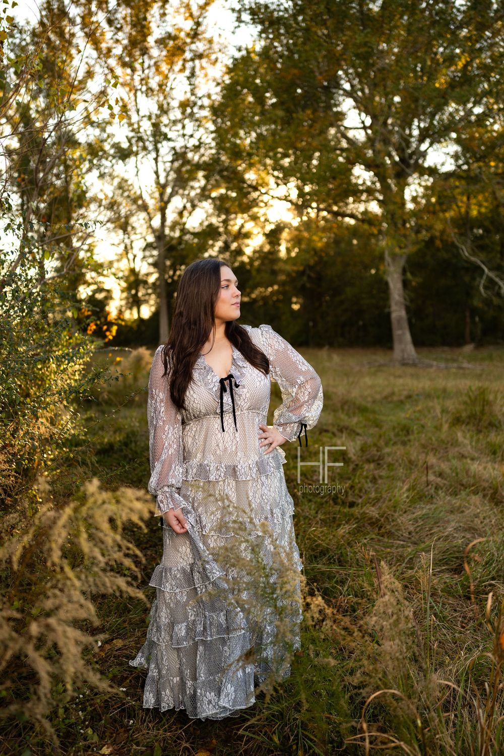 A delicate white lace dress flows gracefully in an outdoor autumn setting during golden hour.
