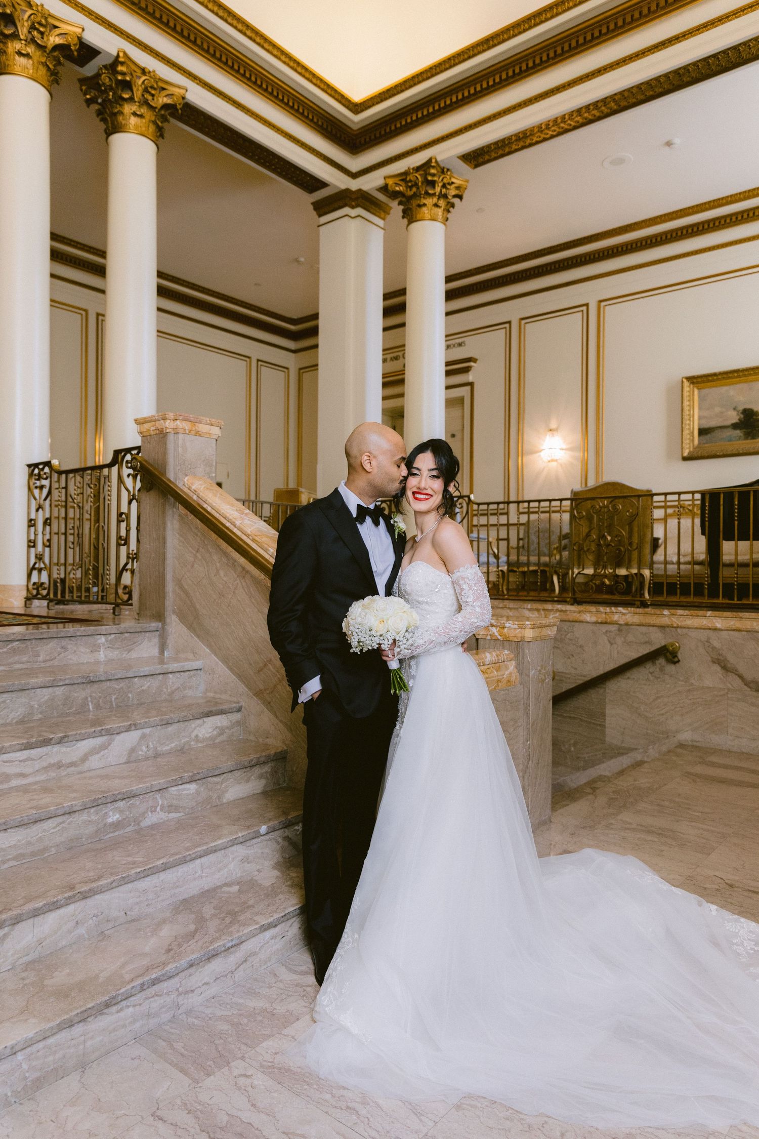 A romantic wedding photo series showing a couple in formal attire posing elegantly on grand marble stairs in an opulent venue.