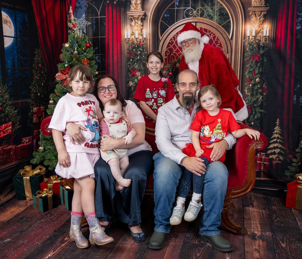 Holiday portraits in an elegant setting with red curtains and ornate decor featuring festive Christmas scenes.