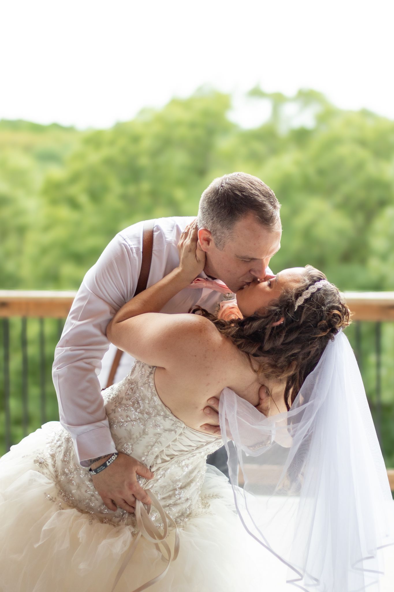 Bride and groom kissing at their wedding in front of trees.