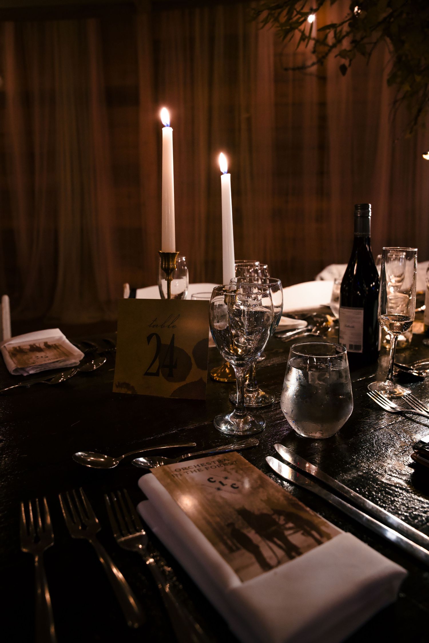 Romantic table setting with candles, wine glasses, and vintage photographs.