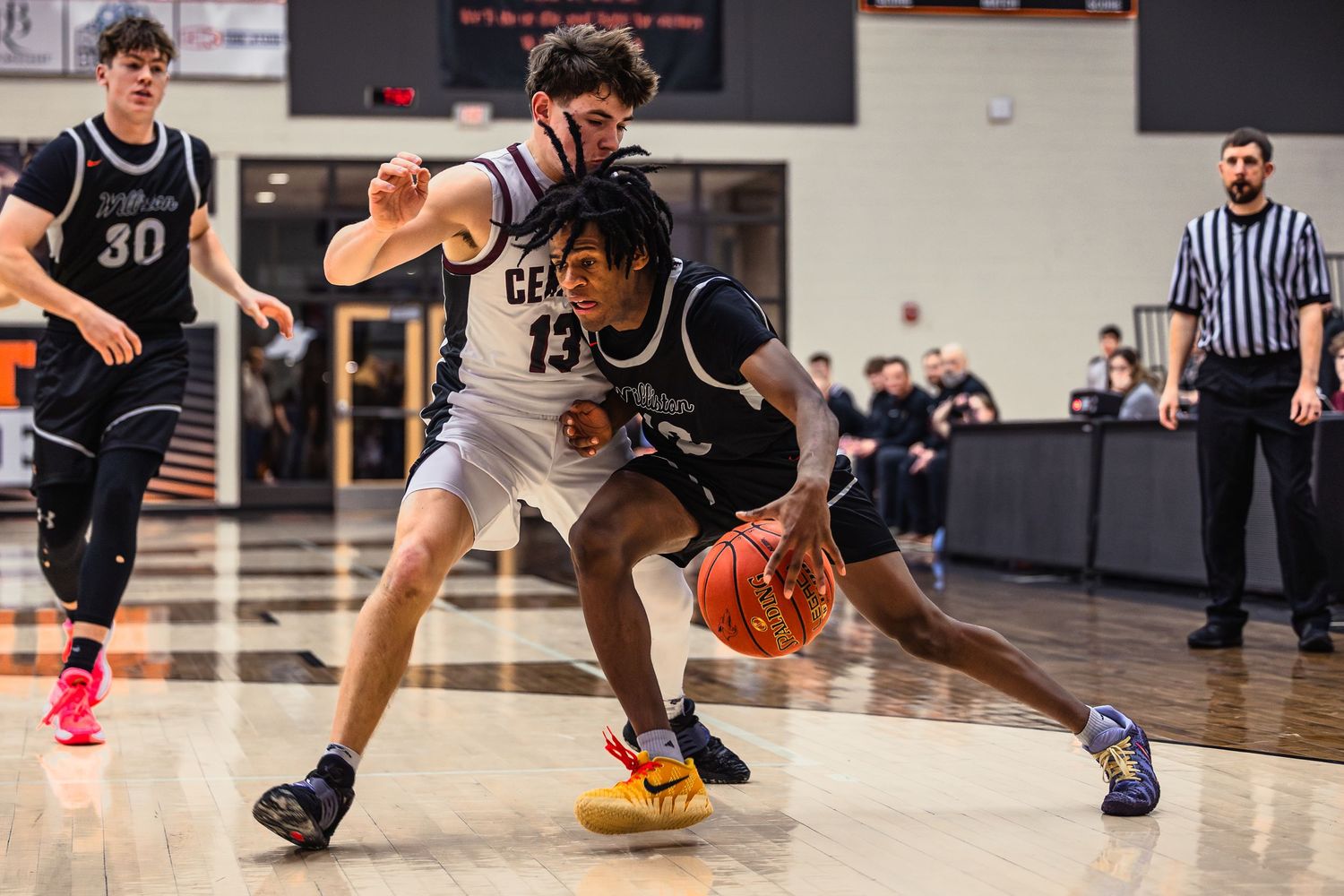 Basketball player dribbles low while making a crossover move on the court during an indoor game.