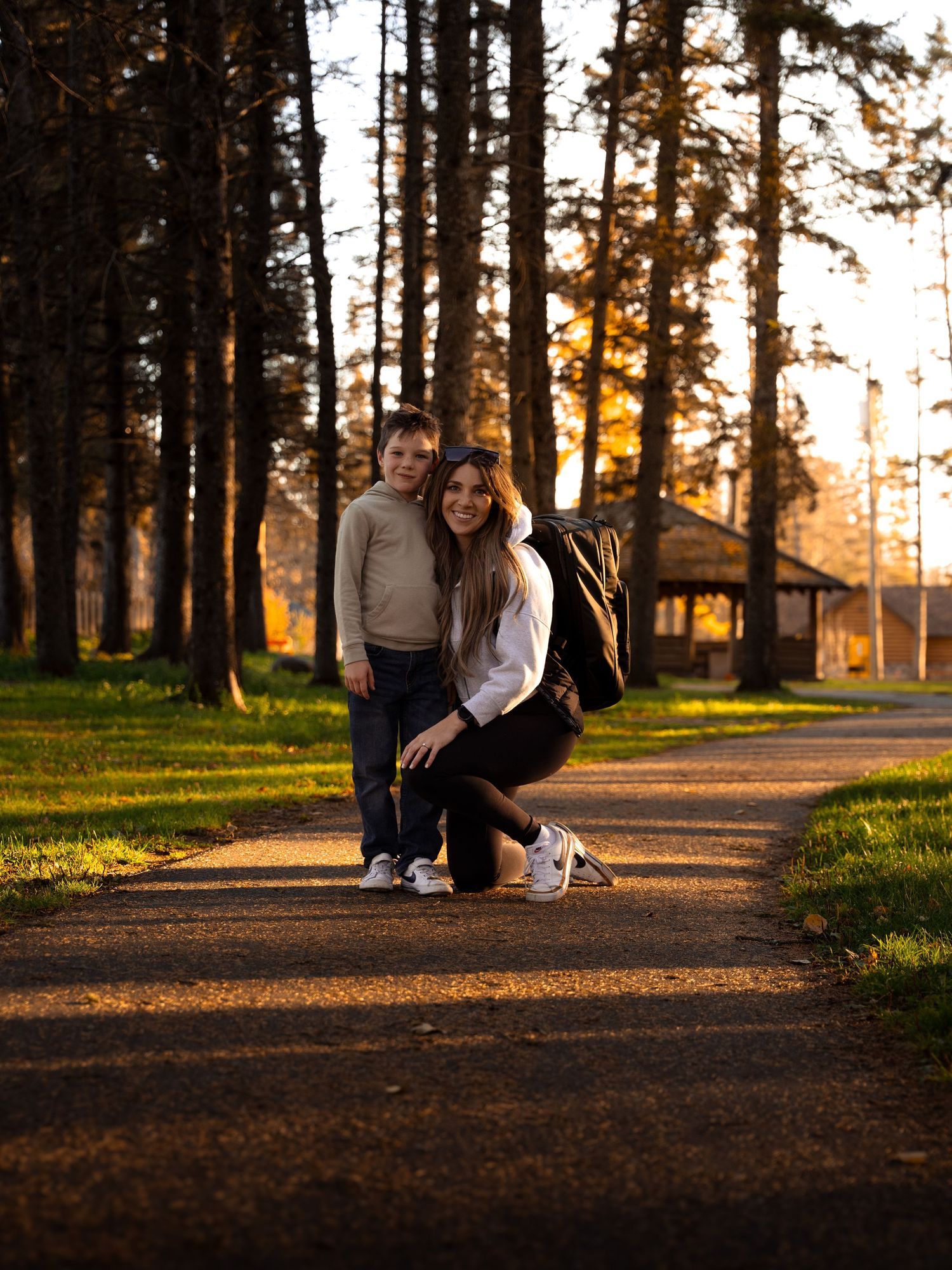 Dirt walking path through pine trees at golden hour.