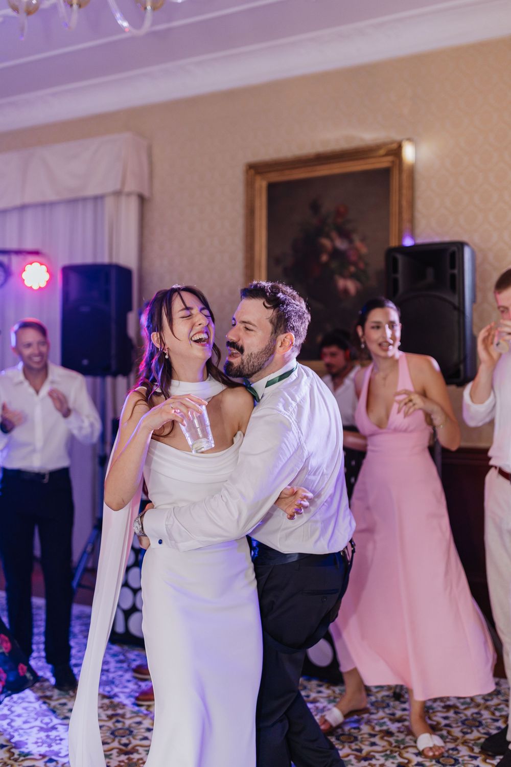 Wedding guests dancing and celebrating on a confetti-covered dance floor at an evening reception.