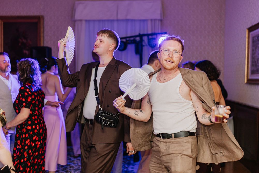 People dancing and celebrating at a wedding reception with colorful lighting and festive atmosphere.