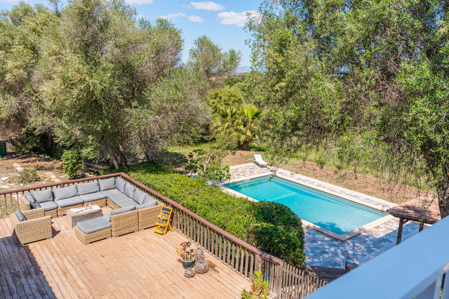 Aerial view of a backyard swimming pool surrounded by trees and wooden deck in a residential property.