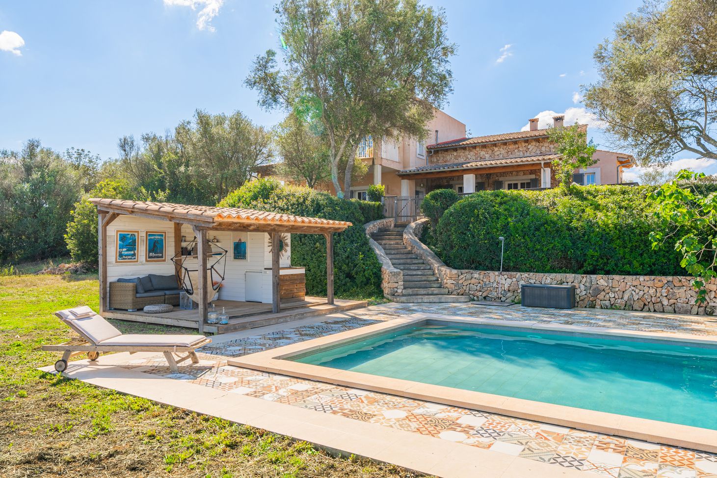 Stunning Mediterranean villa with swimming pool and terrace surrounded by lush gardens and stone walls.