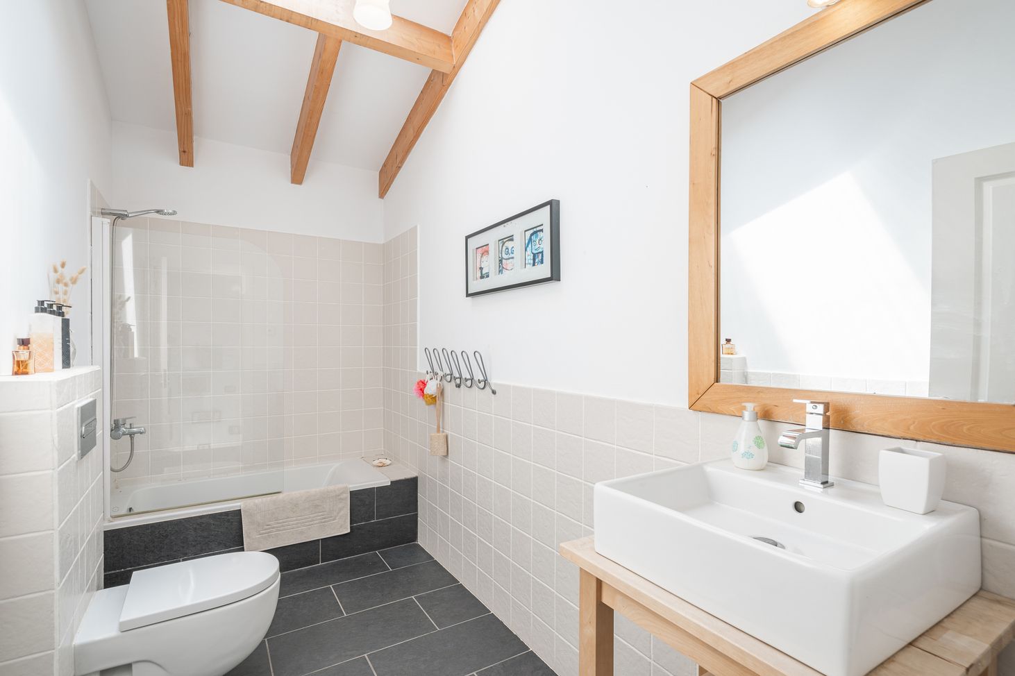 Minimalist bathroom featuring white tiles, wooden accents, and a freestanding modern sink basin.