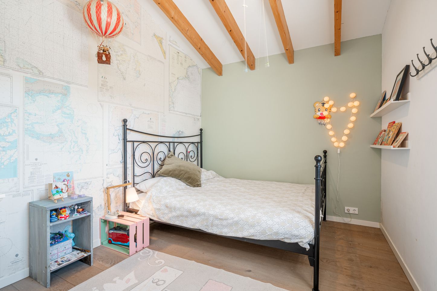 A bright modern bedroom with exposed wooden beams features a white bed, decorative lighting, and built-in storage solutions.