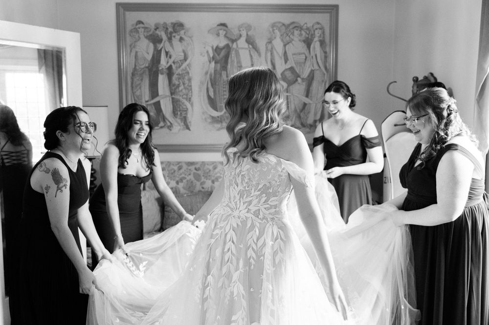 Black and white photo showing bridesmaids helping prepare for a wedding ceremony.