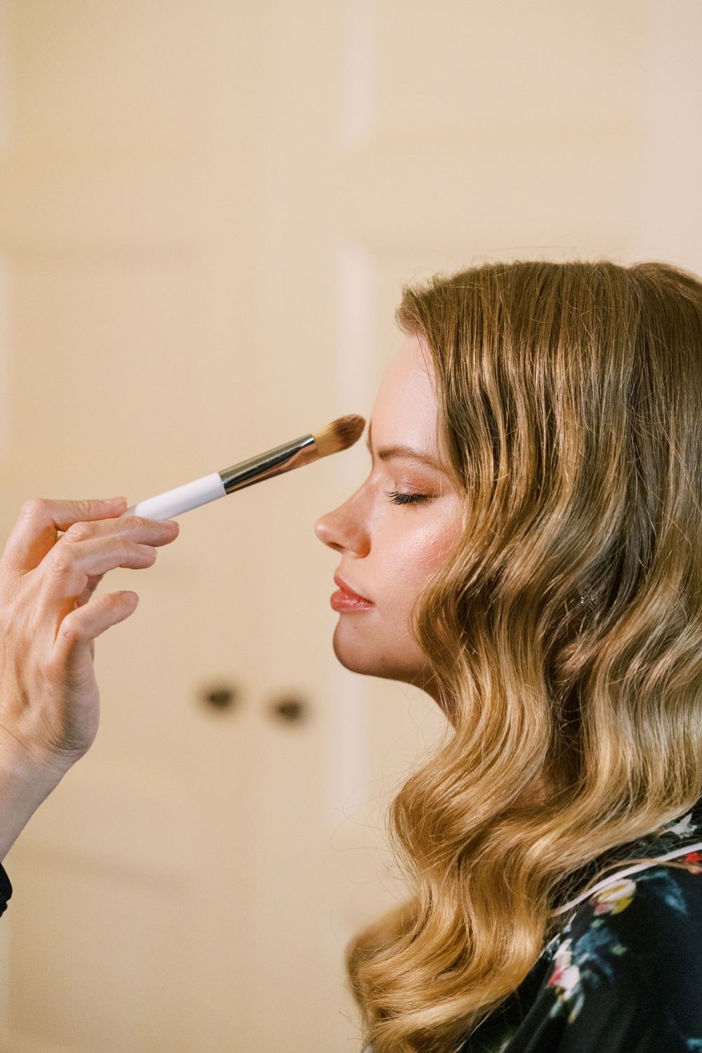 Close-up shots of makeup being applied with brushes during wedding preparation.