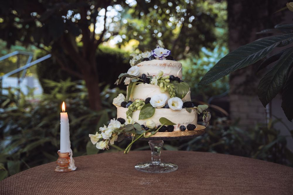 Wedding cake display with candles and floral decorations in a garden setting.