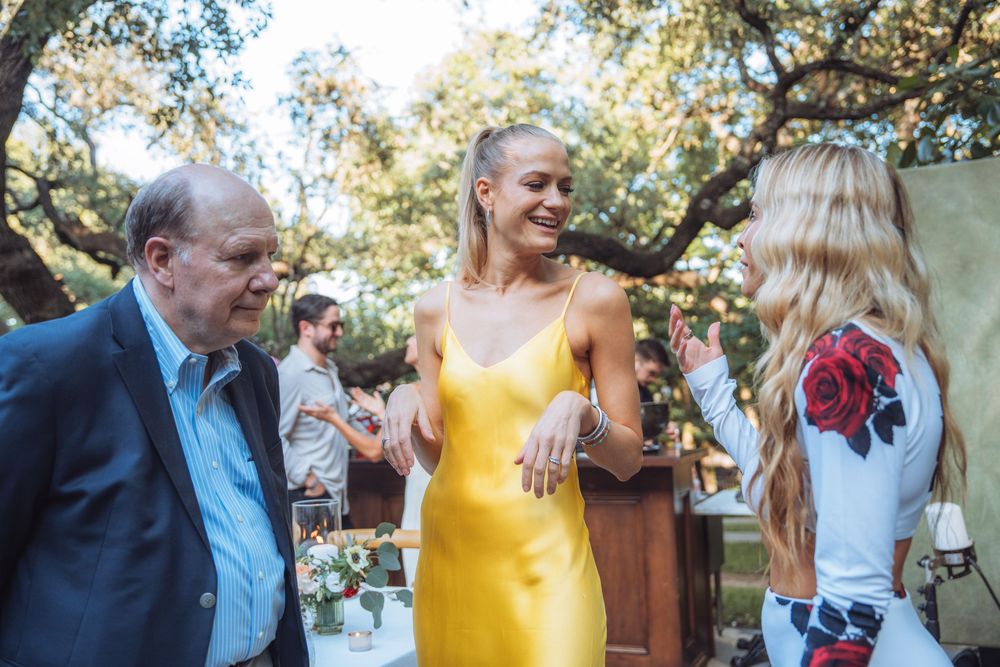 Guests enjoying conversation during an outdoor celebration with natural lighting.
