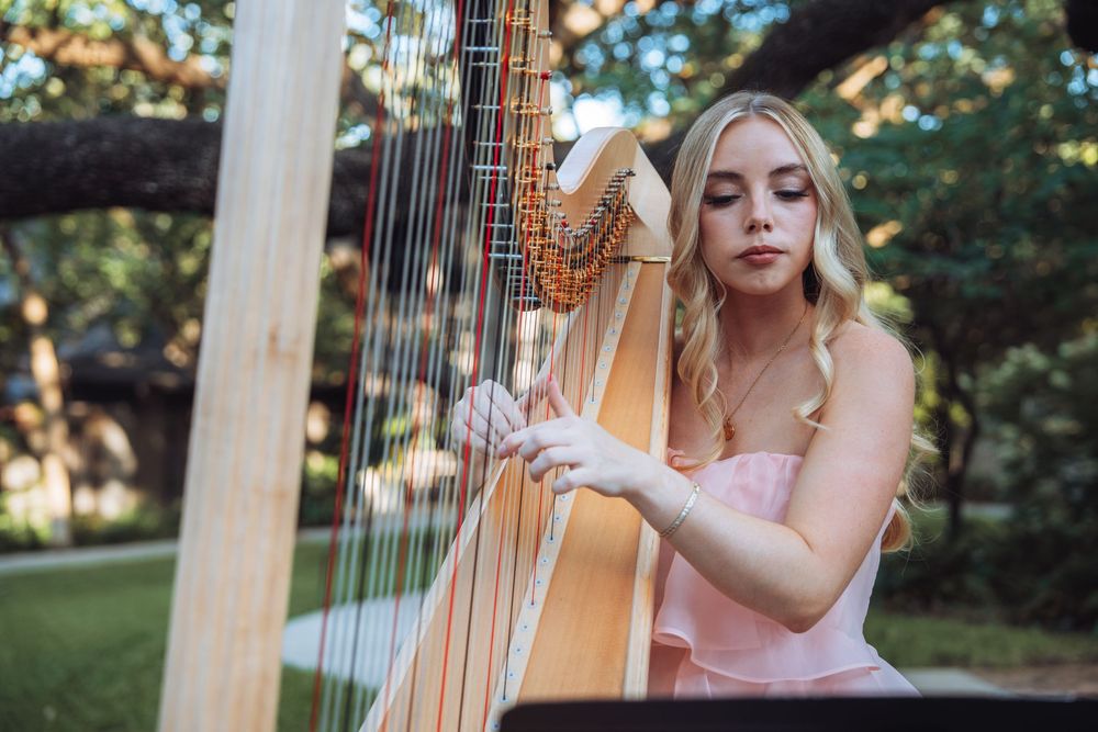 Elegant harp player performing music at an outdoor garden event.