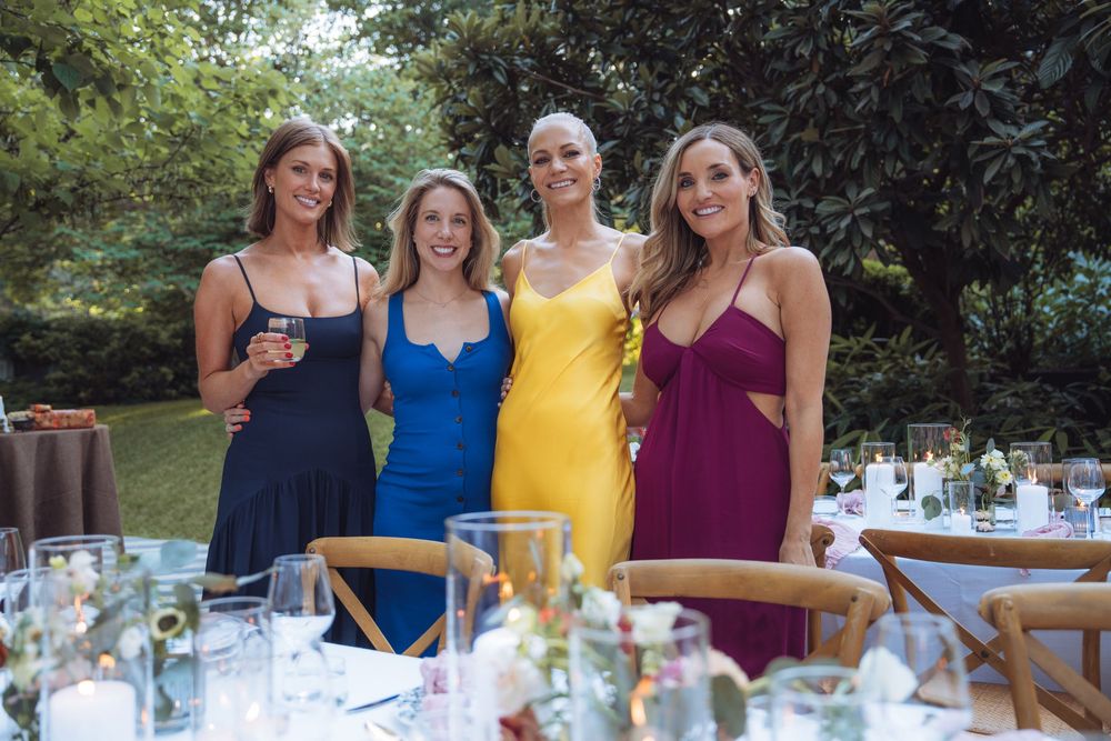 Group of guests in colorful dresses enjoying cocktails at an outdoor celebration.