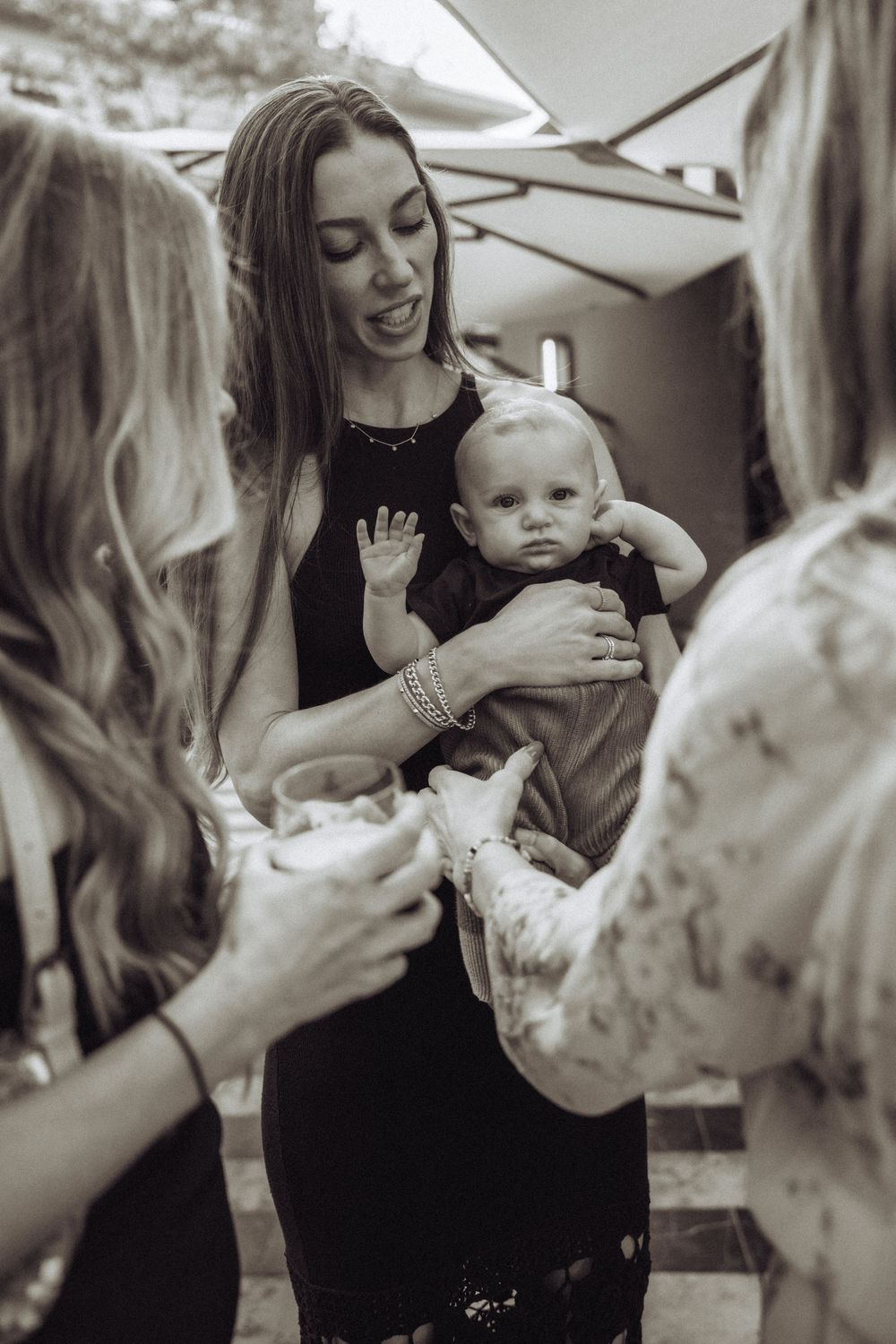 Black and white photo of people gathered around an infant at an intimate gathering.