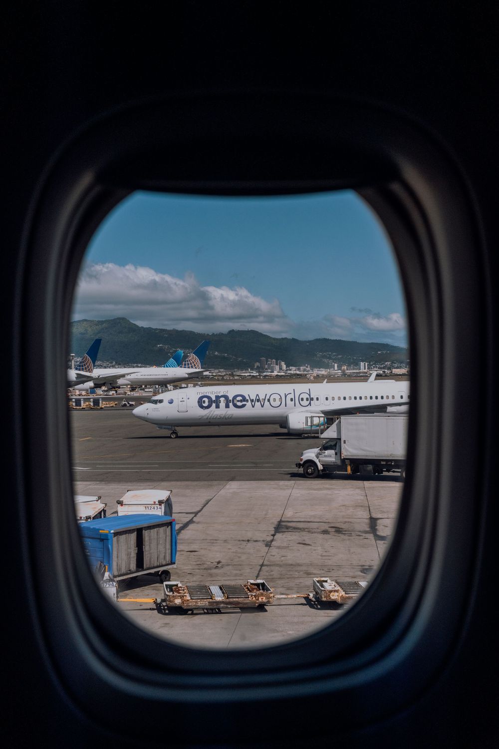 View of commercial aircraft through airplane window frames at an airport tarmac.
