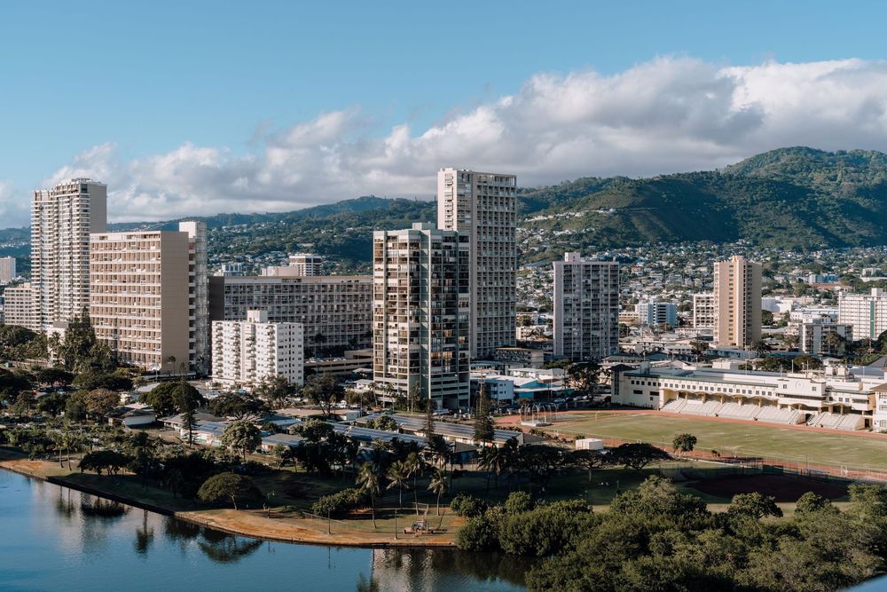 Panoramic cityscape view of Honolulu with high-rise buildings and mountains in the background.
