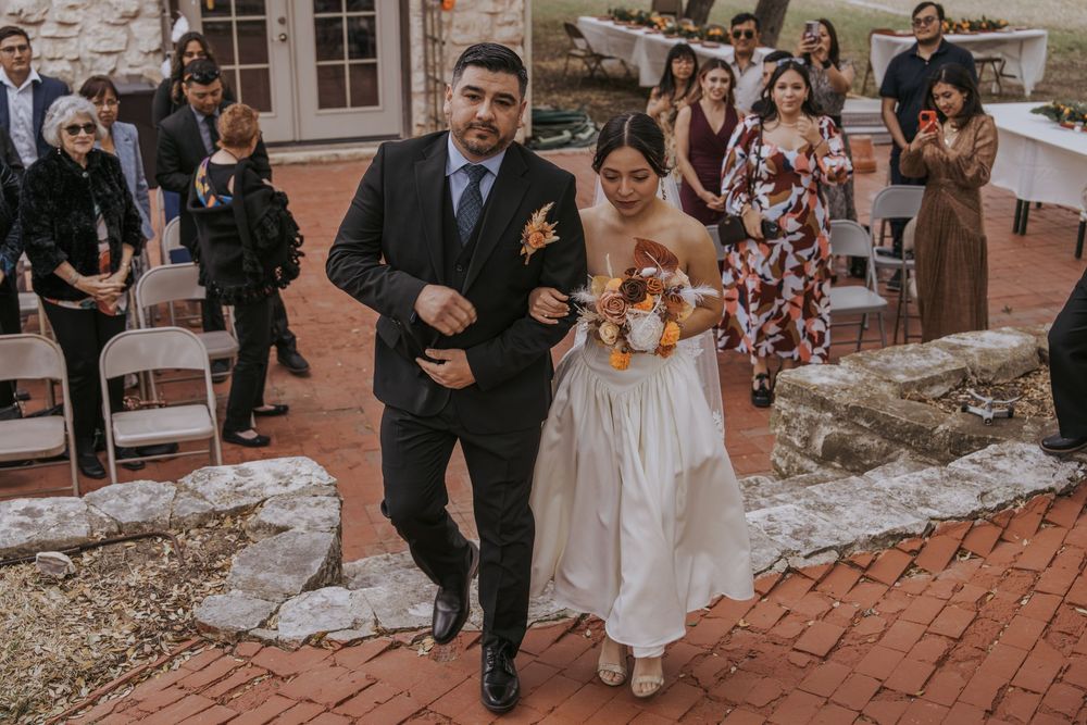 Wedding guests gathered on brick patio outside historic stone building during celebration.