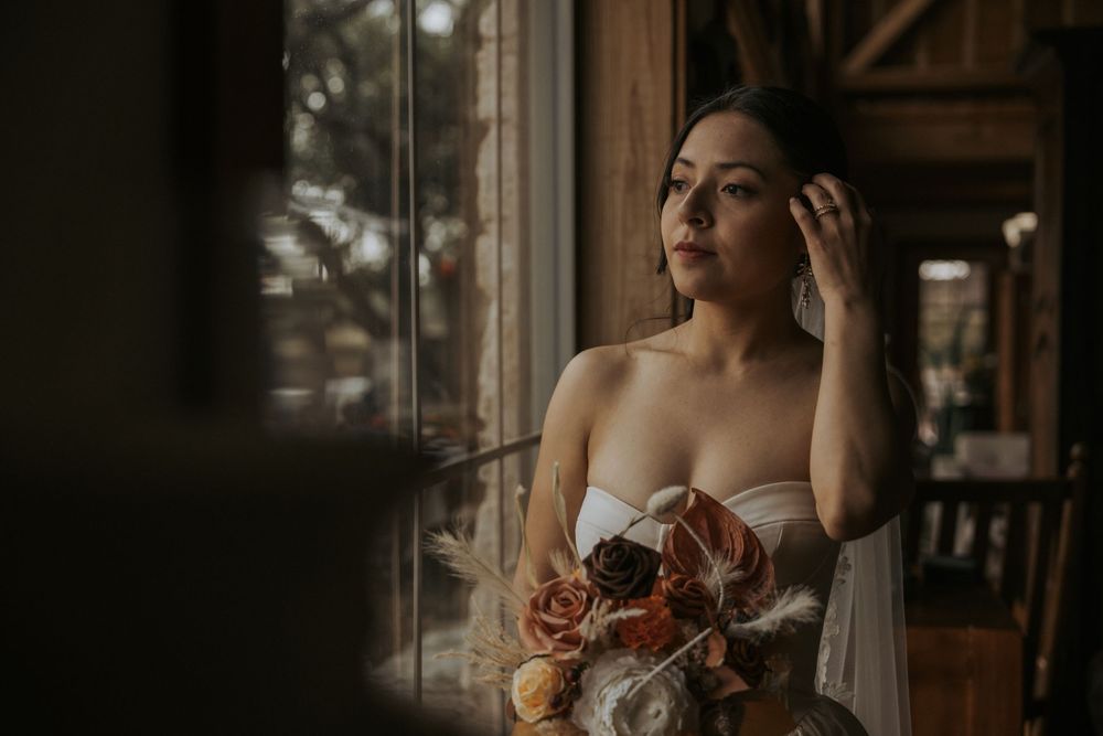 Elegant wedding details captured through window of rustic venue with natural lighting.