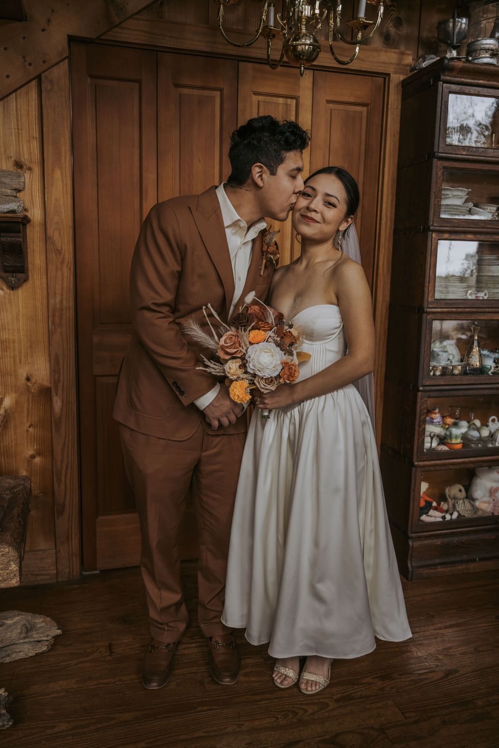 Intimate wedding moment captured in rustic wooden interior with vintage decor.