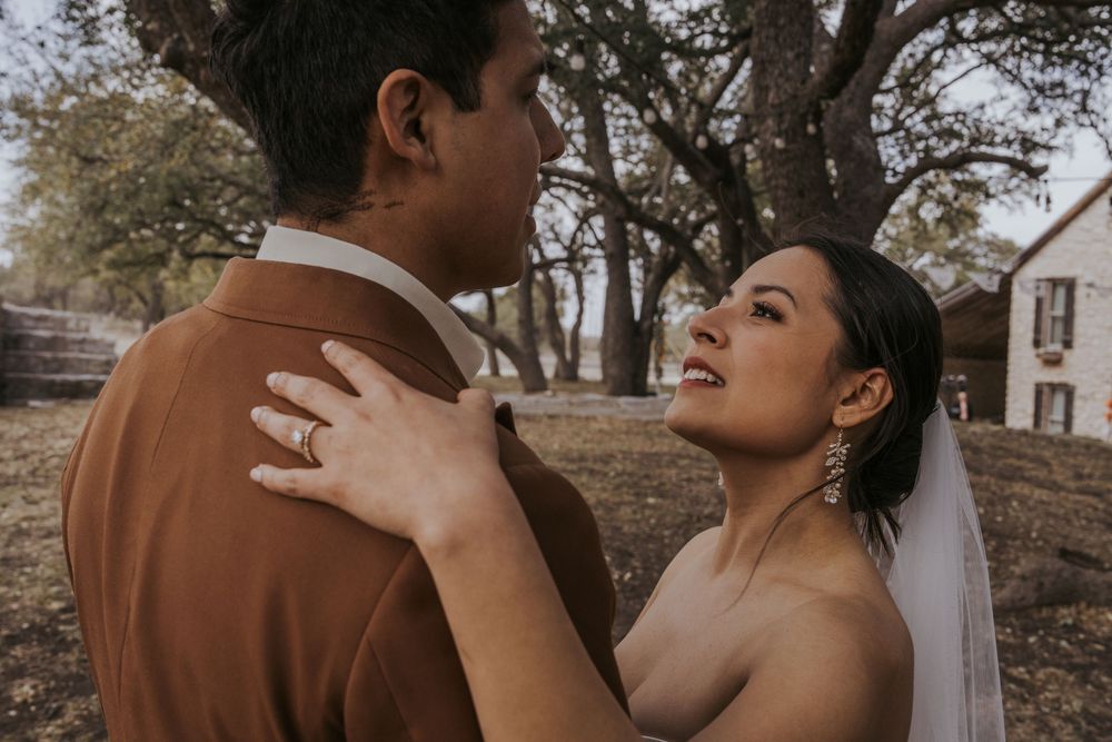 A romantic outdoor wedding ceremony moment with a couple embracing under autumn trees.