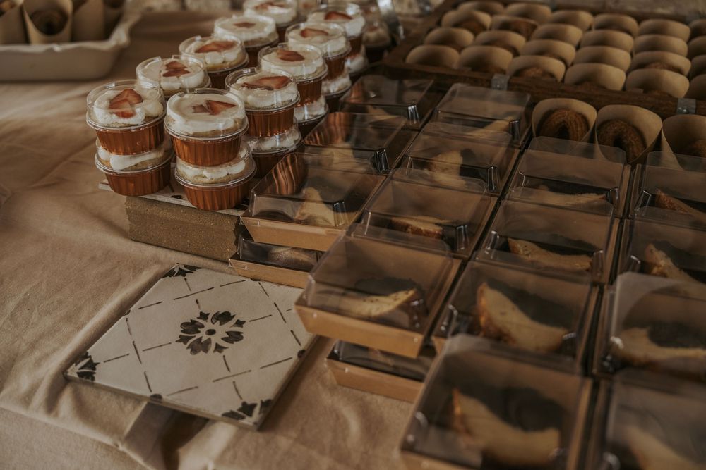 Rows of cupcakes and desserts displayed on wooden tables at a rustic wedding reception.