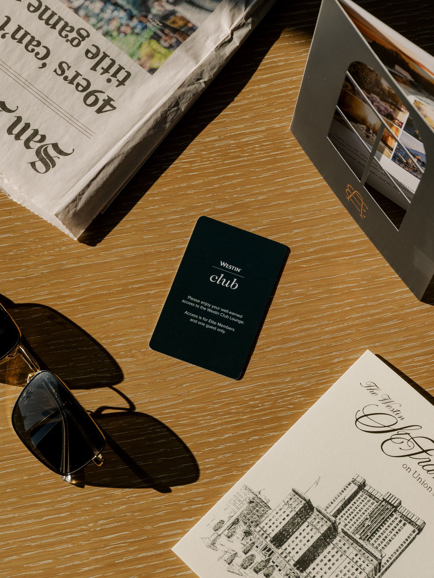 Stylish business cards and branding materials arranged on a wooden surface with dramatic lighting and shadows.