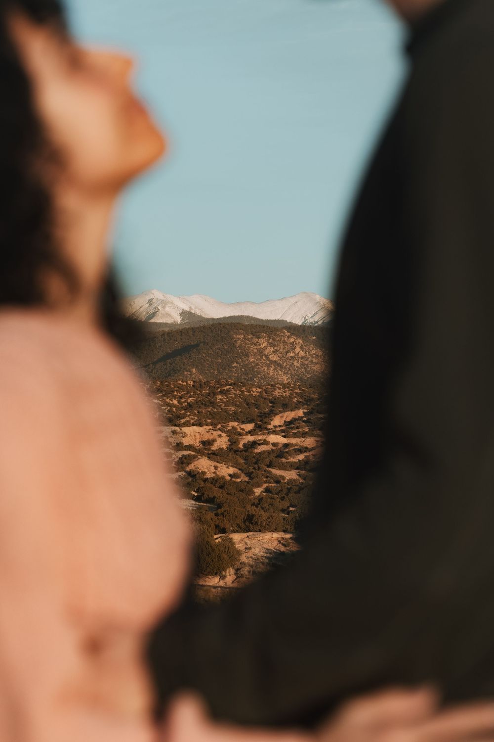 Creative framed shot of snowy mountains through silhouette of couple standing together.