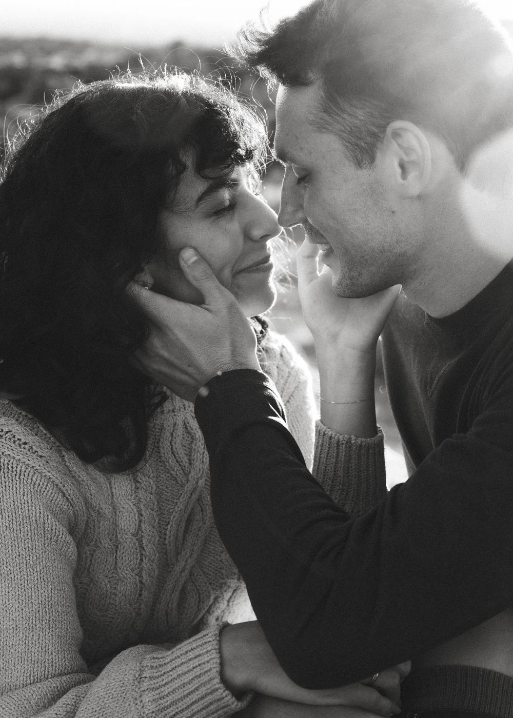 Romantic black and white photo of couple nearly kissing, mans hand cradling womans face.