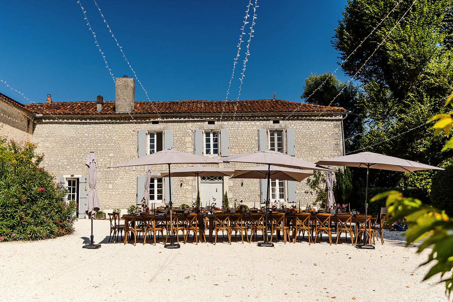 A panoramic view of a rustic French countryside estate with stone buildings and lush gardens.