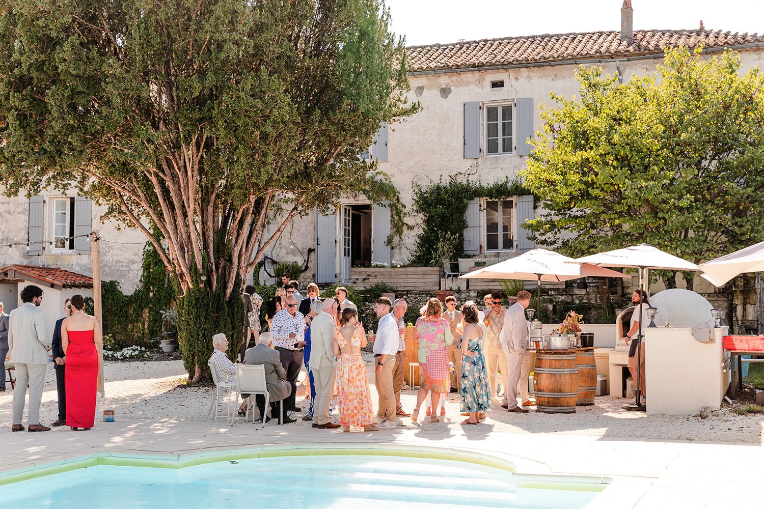 Wedding guests gather in a charming Mediterranean courtyard with terracotta tiles and white stone buildings.