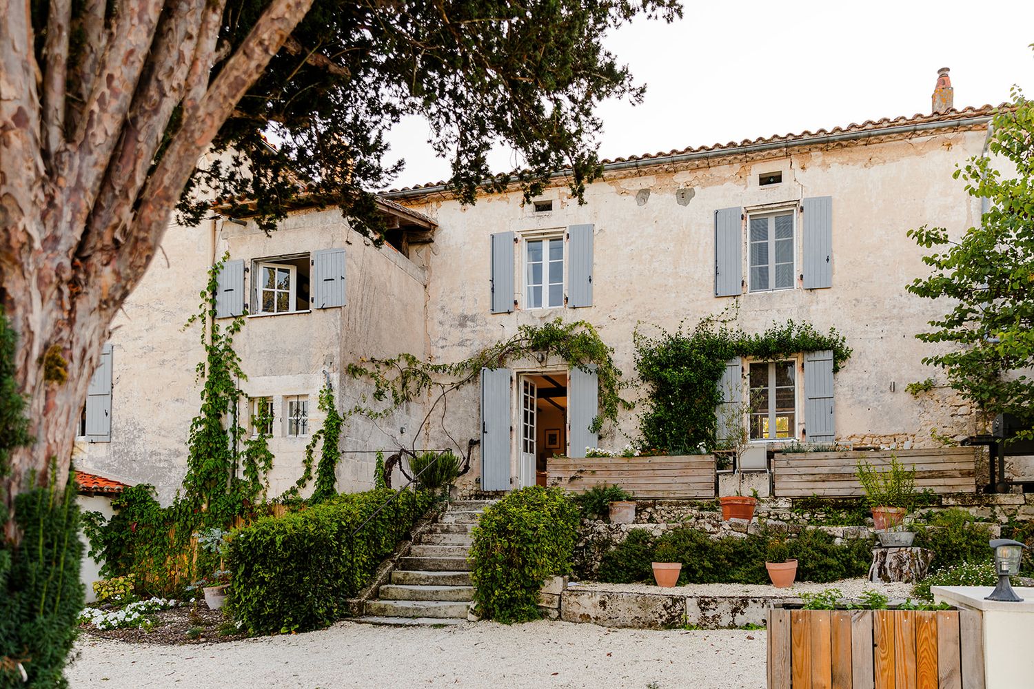 Stone buildings and pathways wind through a charming Mediterranean village with rustic architecture and potted plants.