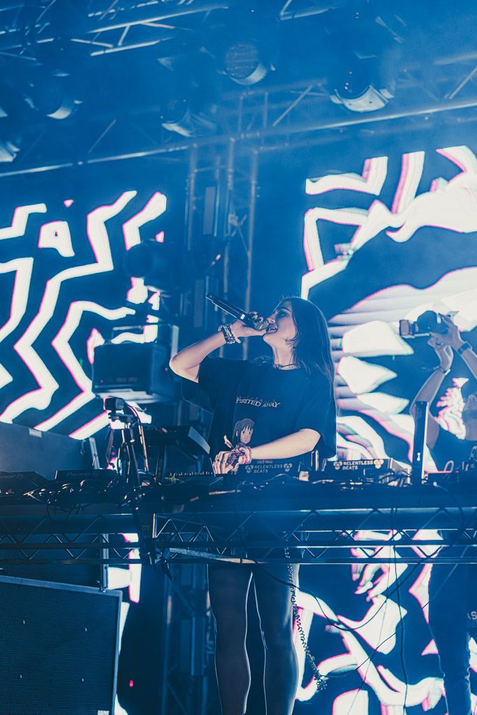 Concert stage with blue lighting and geometric patterns displayed on large screens during a live performance.