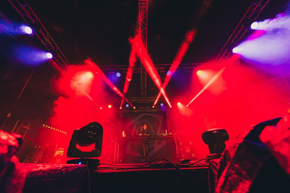 Concert stage illuminated with vibrant red and purple lighting effects creating a dramatic atmosphere during a performance.