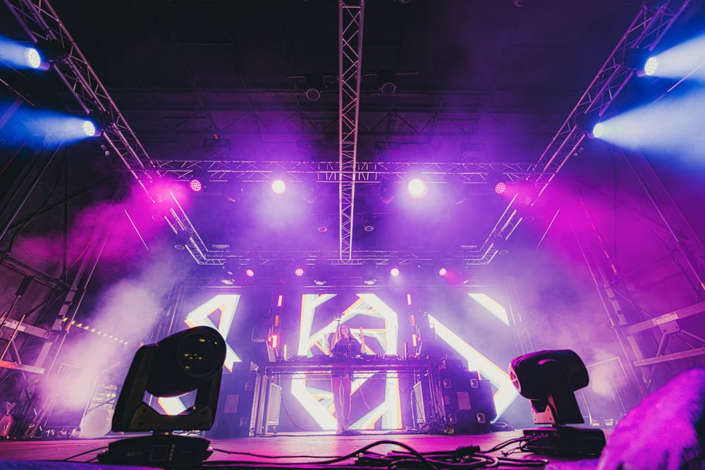 Concert stage illuminated with vibrant purple and blue lighting effects during a live music performance.