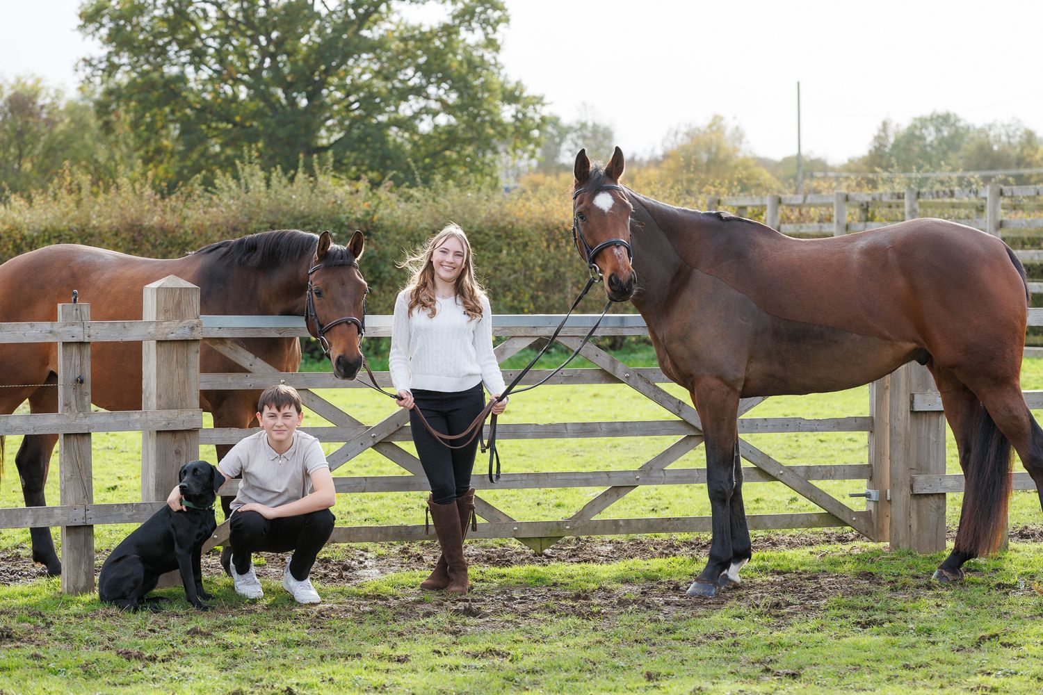 A horse and its rider enjoy an outdoor photoshoot session near rustic wooden fencing on a sunny day.