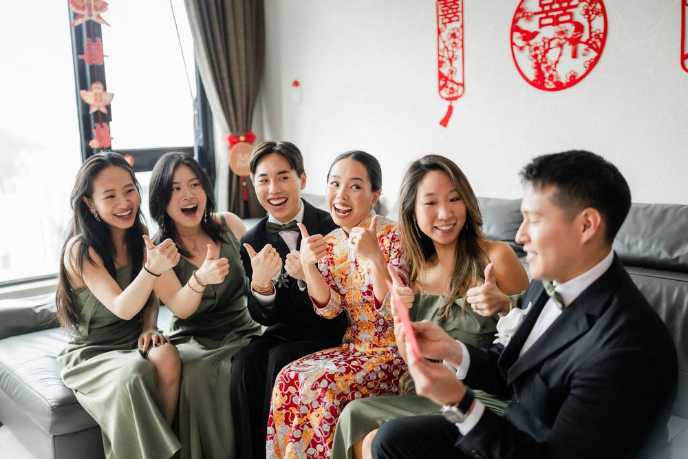 Bride in qipao celebrating with bridesmaids and groom during Chinese wedding games.