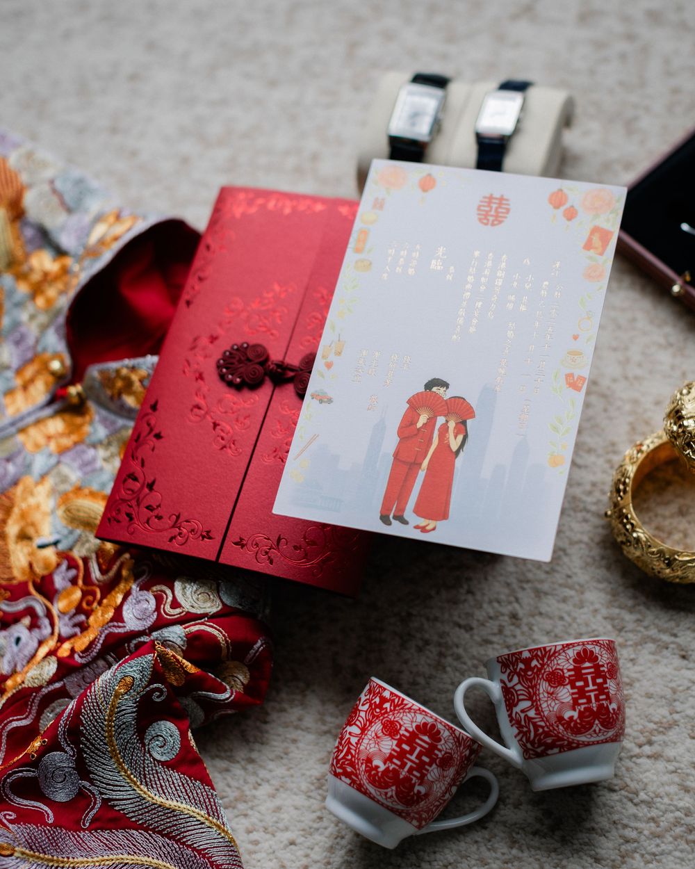 Traditional Chinese wedding flat lay with red invitation, tea cups, bangles and decorative accessories.