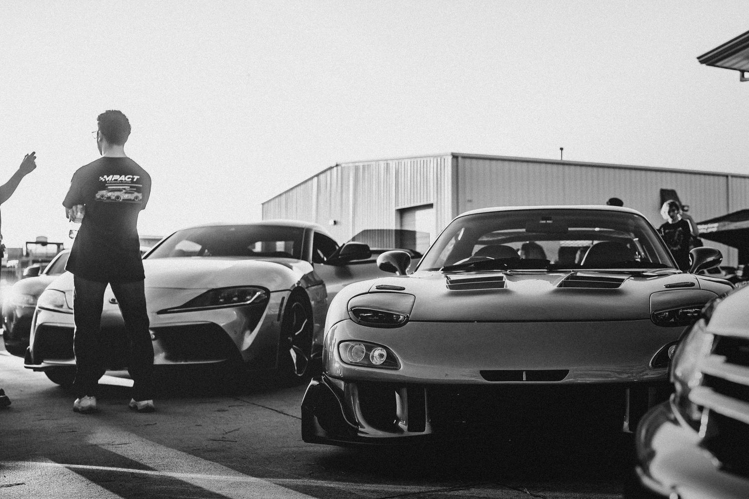 A line of luxury sports cars and performance vehicles parked in a row at a car meet or auto show event.