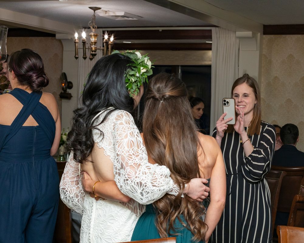 A bride is candidly photographed with friend  during reception at Colonial Inn in Concord, MA.  Refined, elegant true to color photography.