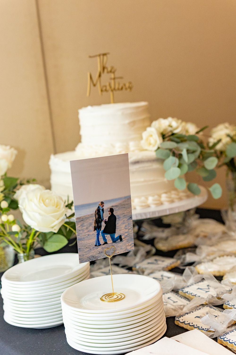 White stacked plates and floral arrangements on a lace tablecloth create an elegant place setting at an engagement party.