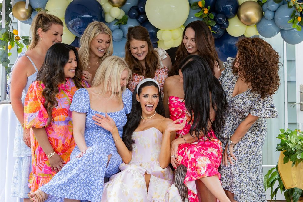 Bride poses with maids while playing games at an at home bridal shower in Boston, MA.  Small event photography Boston and Metrowest area.