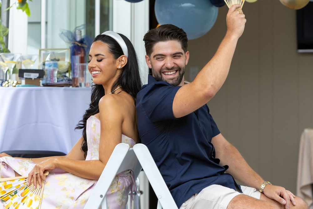 Bride and Groom laughing while playing games at an at home bridal shower in Boston, MA.  Small event photography Boston and Metrowest area.