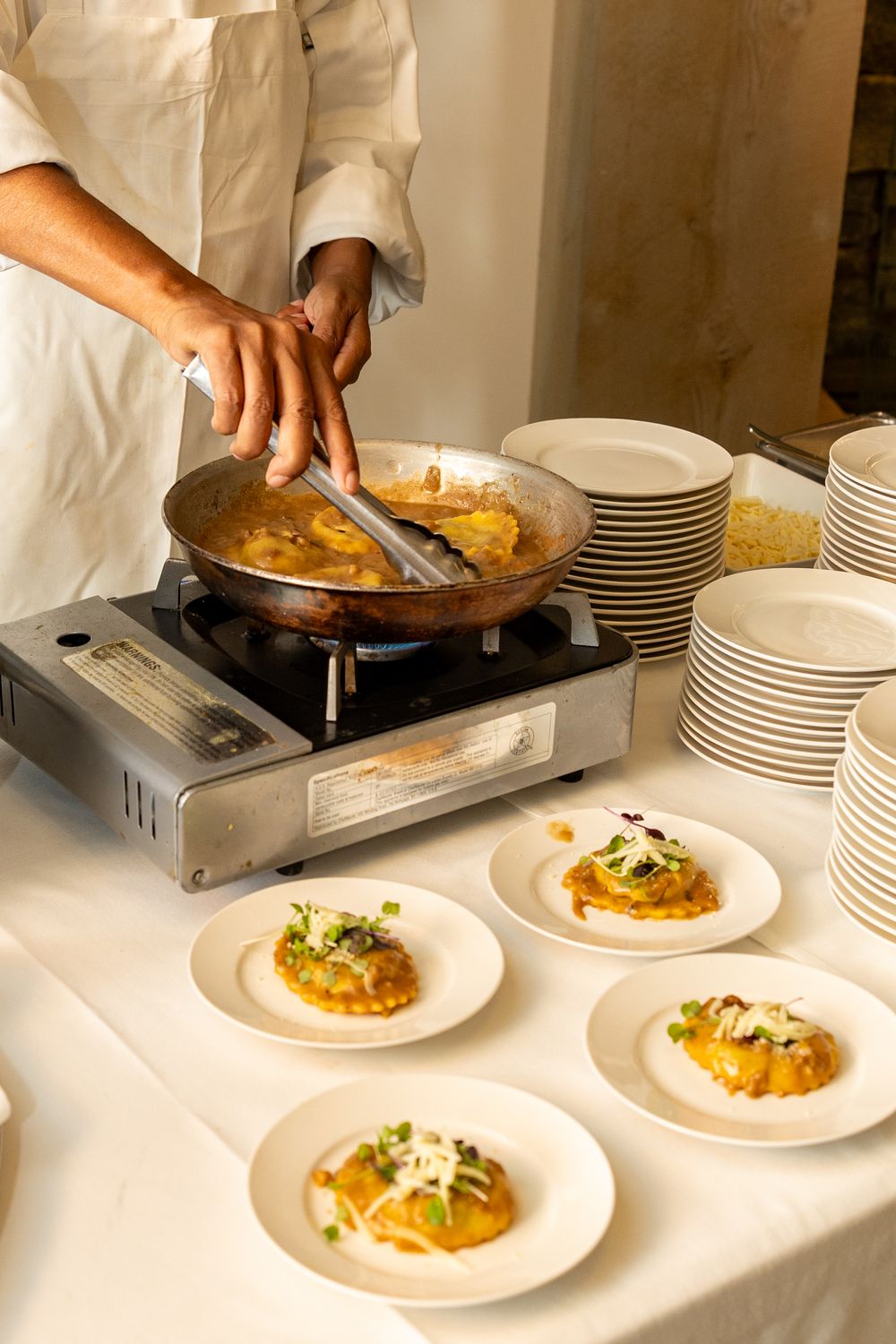 Chef plates gourmet appetizers on white dishes, showing a sequence of plating steps from left to right.