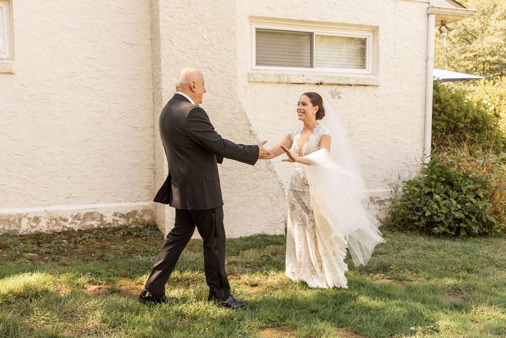 A couple takes romantic outdoor photos against a white building exterior.